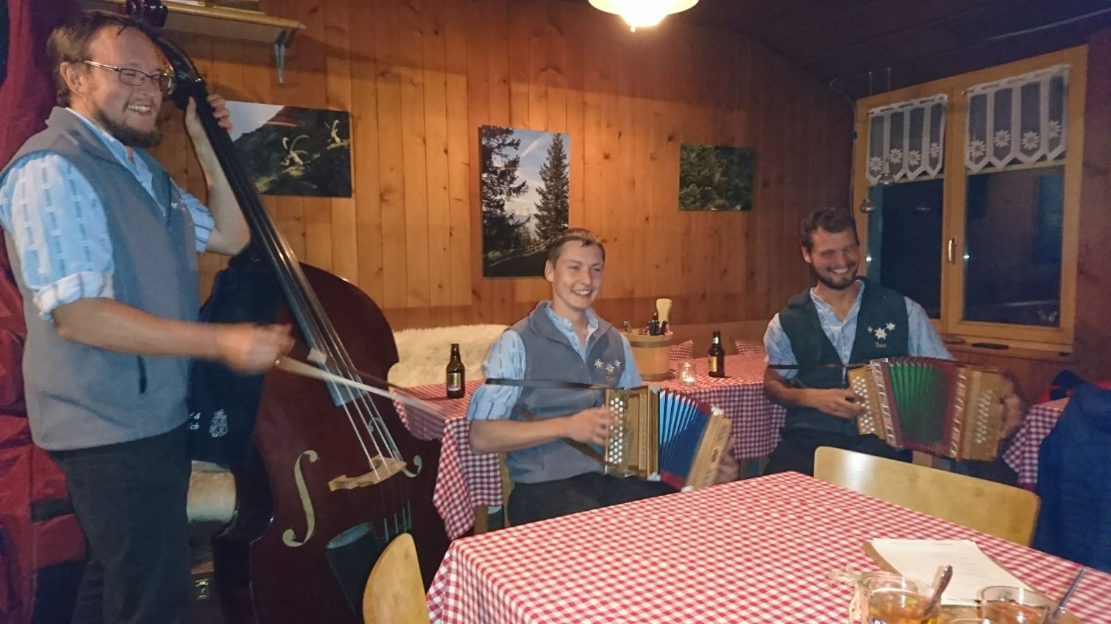 Ländlermusik in einer Stube: Kontrabass und zwei Schwyzerörgeli an gedeckten Tischen
